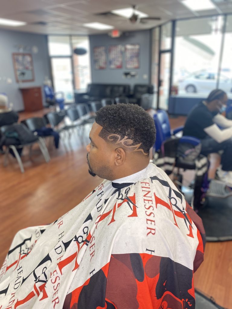 Client in a barber chair looking to the side to capture the new haircut and the hair design.