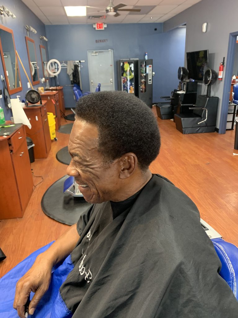 Client facing the mirror smiling at himself after a haircut.